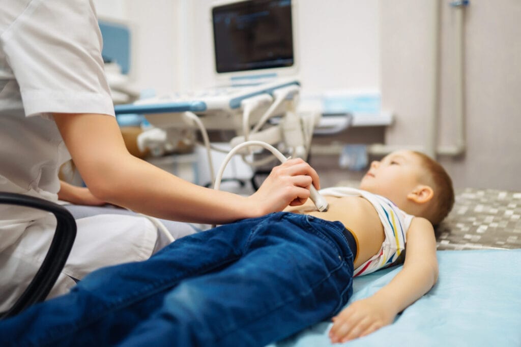 boy undergoing ultrasound examination. doctor examining kid stomch in clinic with equipment before Appendectomy.